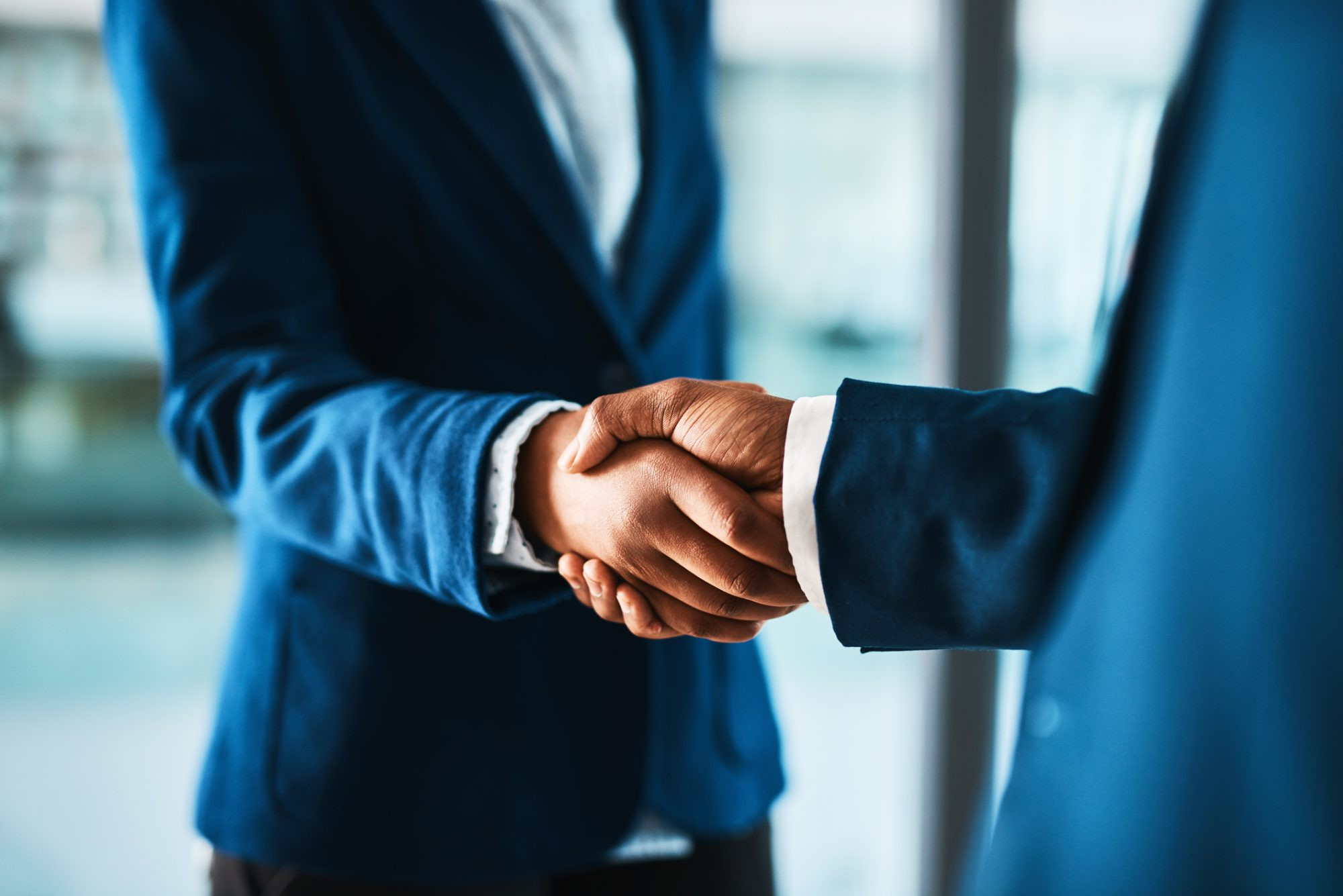 Cropped shot of two businesspeople shaking hands in a modern office